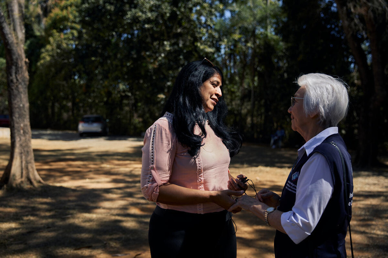 Dos mujeres se toman de la mano mientras conversan en un jardín a la sombra
