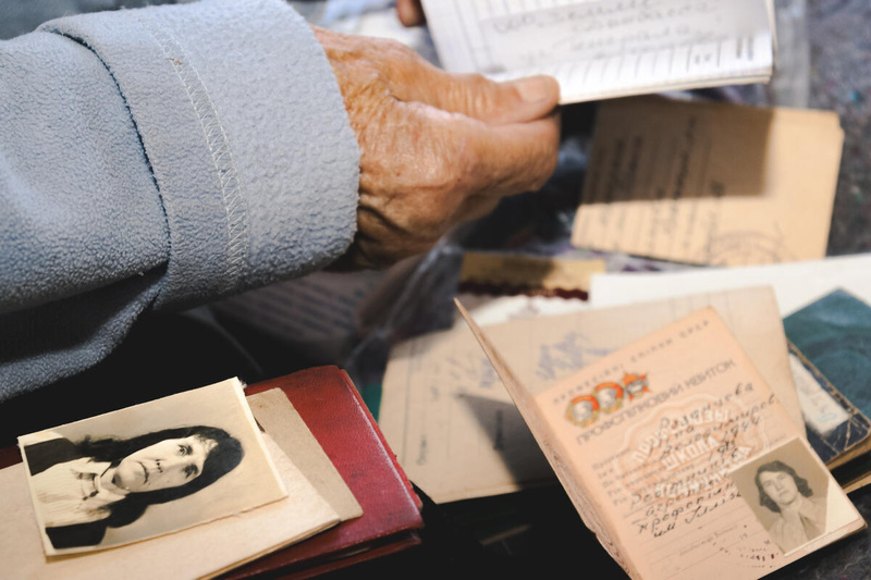 Una mano sostiene un documento mientras se extienden otros documentos y una foto antigua