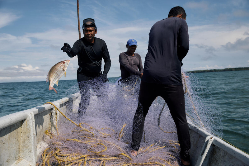 Tres hombres pescando sobre una embarcación en Colombia