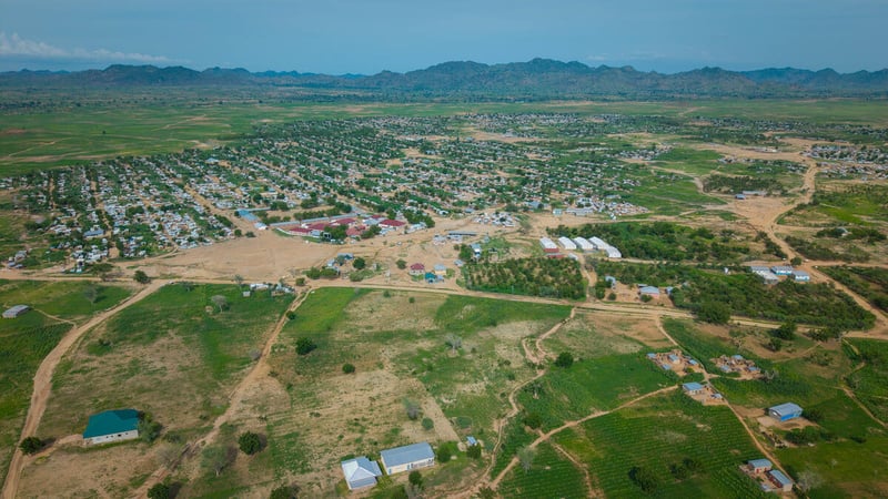 Vista aérea de un asentamiento entre verdes campos, con colinas a la distancia