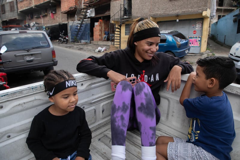 Andriuska y sus hihos conversan sonriendo en el cajón de un pick-up que usan como transporte.