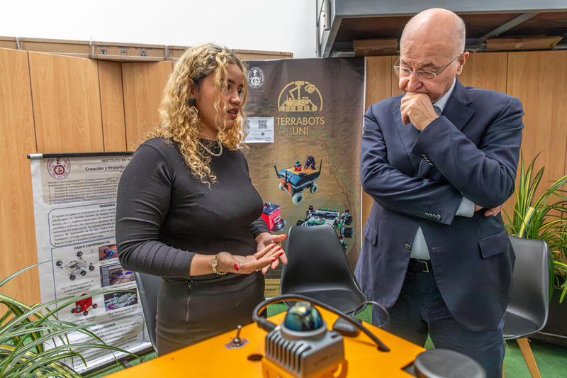 Yuliveth conversa con el Alto Comisionado Barham Salih delante de una mesa donse se ebcuentra un pequeño robot.