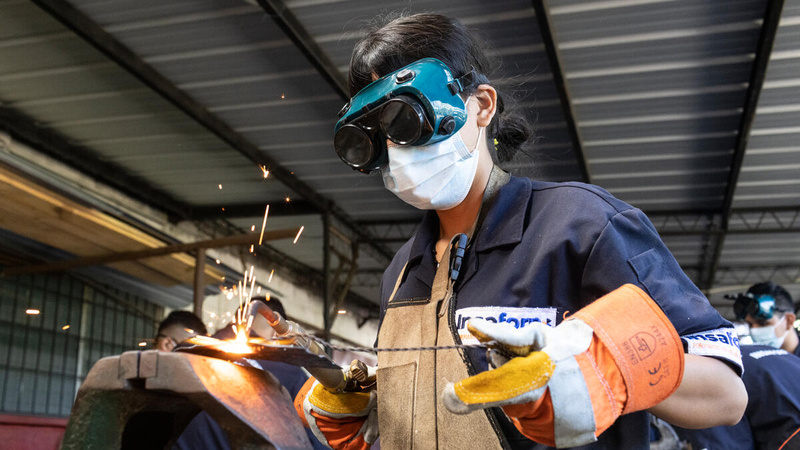 Una mujer, que lleva puestas gafas de protección, trabaja en una soldadura en un taller mecánico