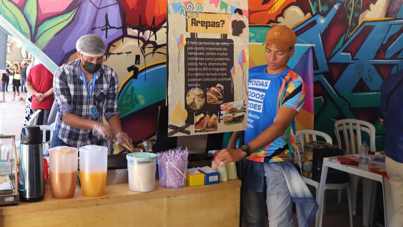 Dos chicos de Venezuela atienden un puesto de comida de su país en una feria de emprendimientos en Brasilia