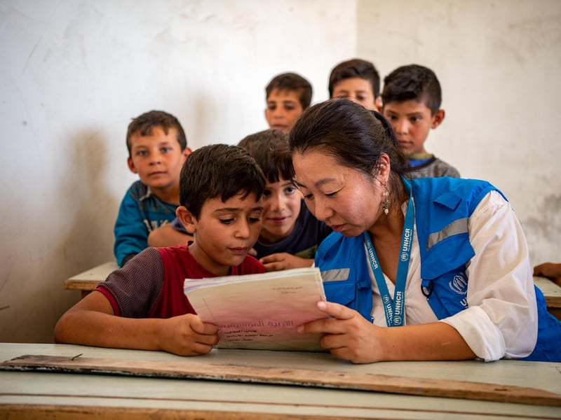 Integrante de ACNUR lee un libro con un niño, en Alepo, Siria.