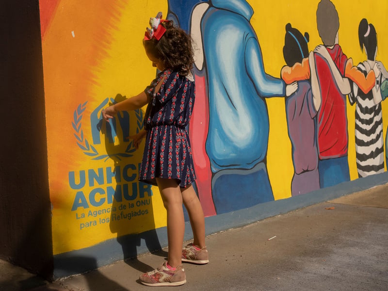 Una niña de espaldas hacia una pared de colores 