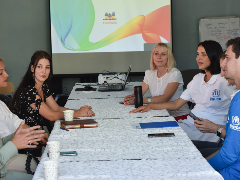 Una grupo de personas tiene una discusión en una mesa larga color blanco
