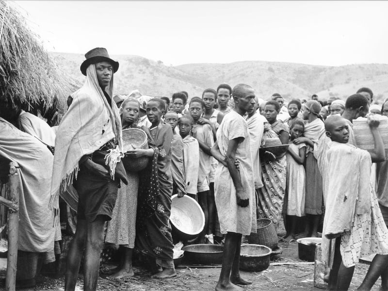 Foto a blanco y negro de decenas de personas que esperan recibir alimentos 