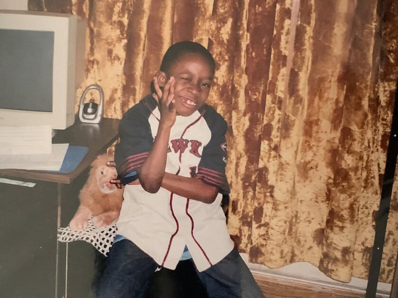 Un niño afro hace muecas frente a la cámara de lado de un computador