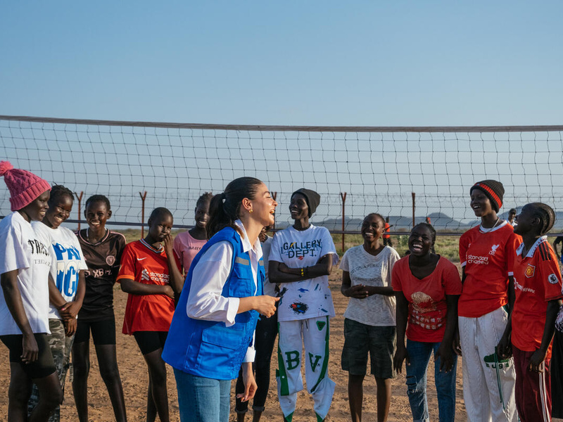 Una joven siria se ríe con un grupo de jóvenes africanas en una cancha de voleibol