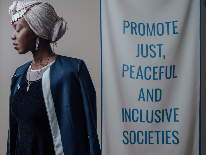 Una mujer sudanesa-estadunidense mira hacia un costado; a la derecha, una pancarta que dice: "Promoción de sociedades justas, pacíficas e inclusivas".