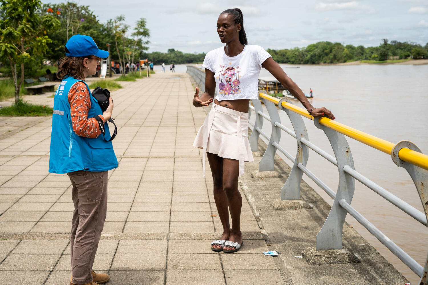 Una trabajadora de ACNUR charla con otra mujer junto al río.