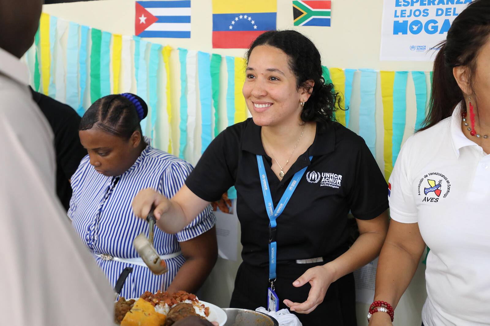 Carla, Asociada de Protección Comunitaria de ACNUR en República Dominicana, brinda alimentos a personas refugiadas durante el encuentro comunitario por el Día Mundial del Refugiado 2023.
