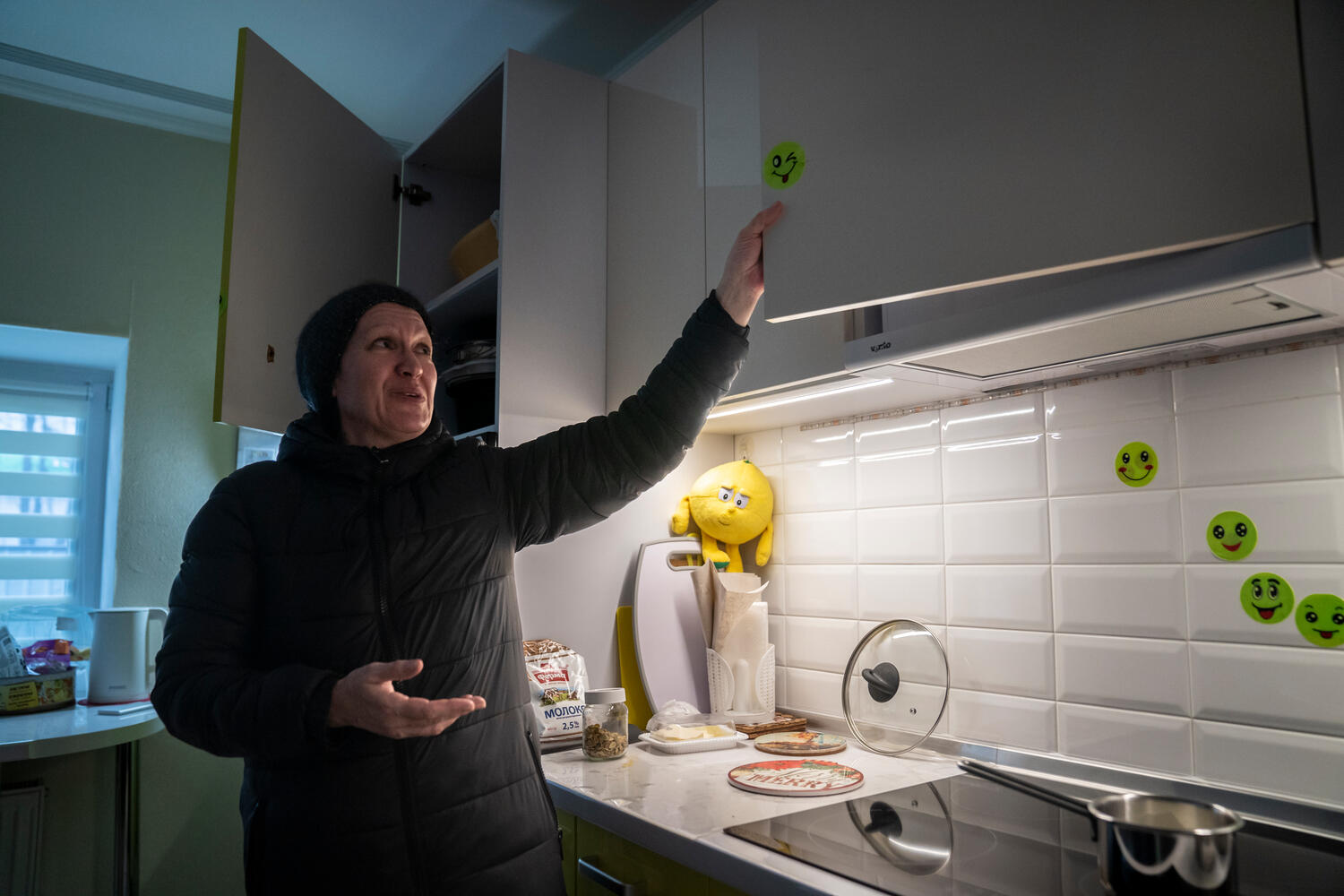 Una mujer señala las pegatinas que cubren los daños causados por municiones en la cocina de su casa.