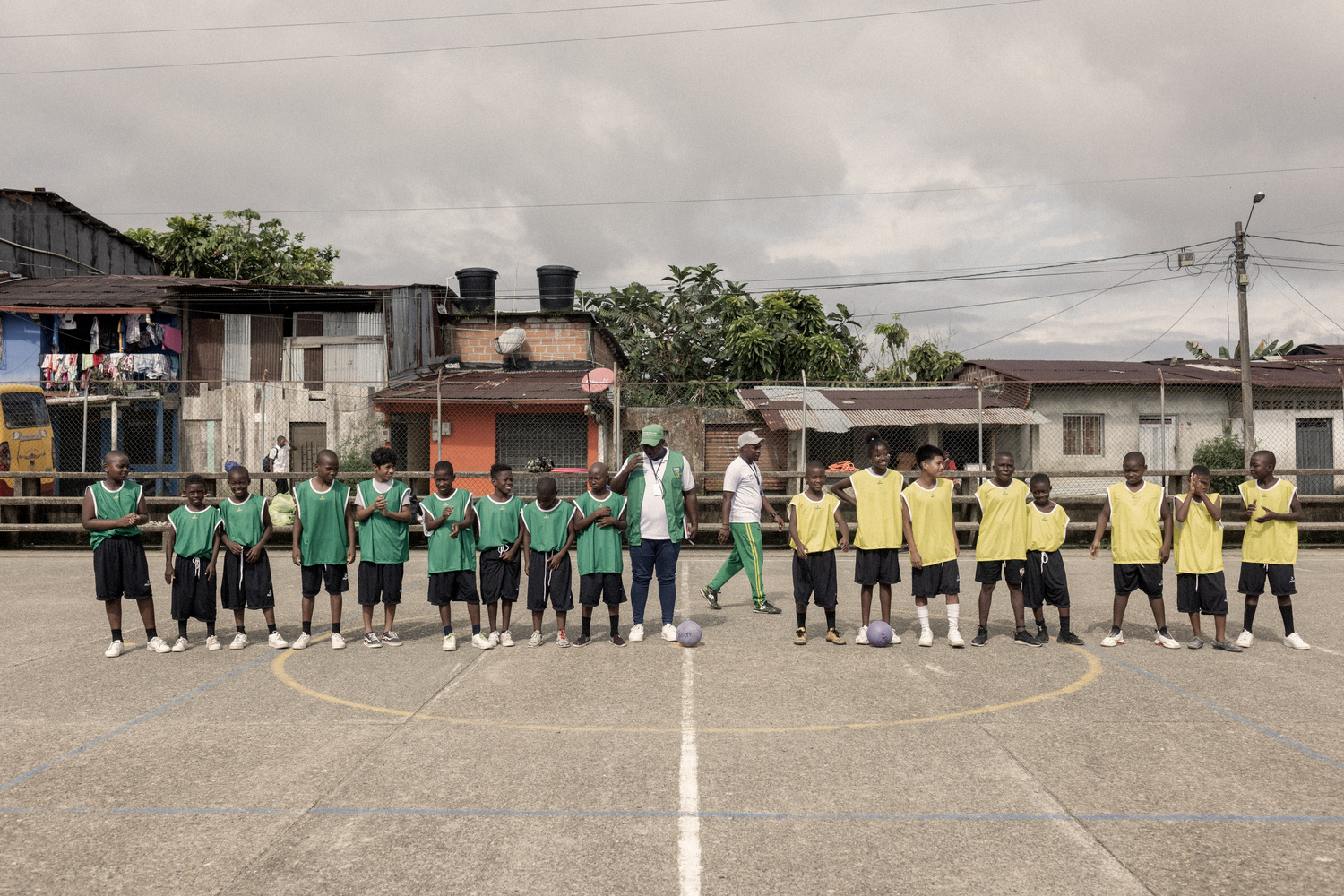 Ni&ntilde;os con uniforme verde por un lado y amarillo por el otro se preparan para jugar un partido de f&uacute;tbol.