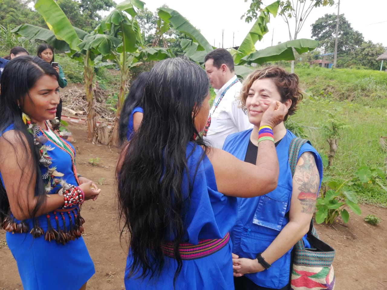 Tres mujeres. Una de ellas pinta el rostro a otra.