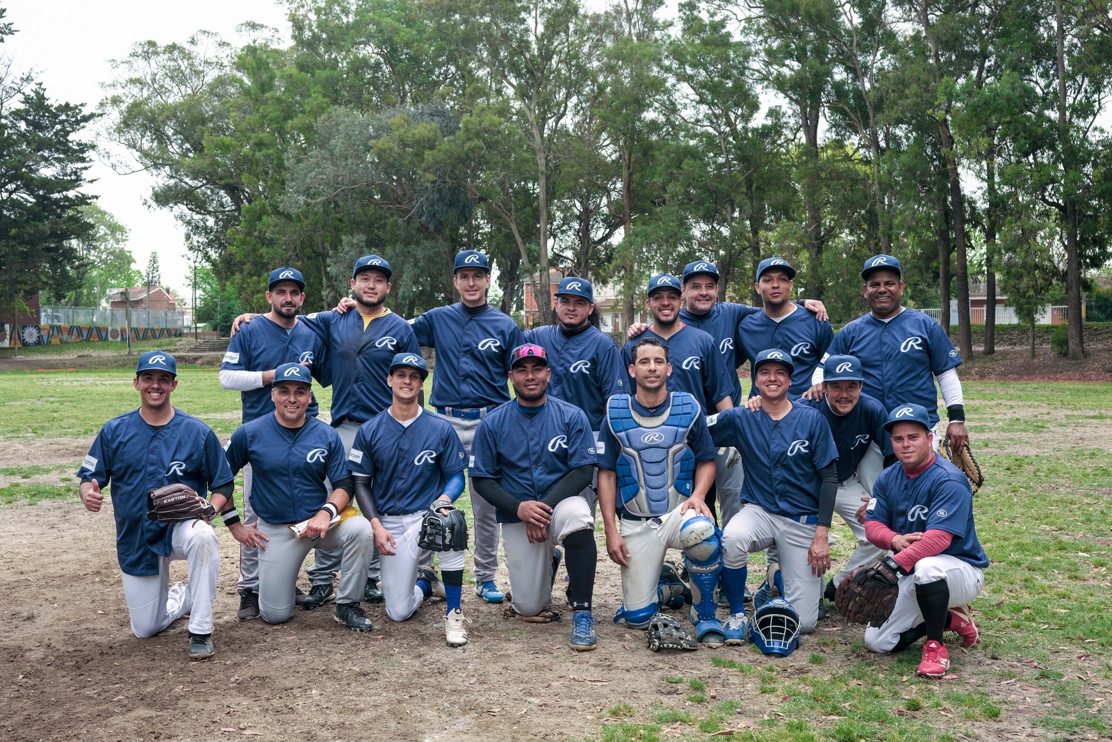Un grupo de jugadores de softbol posan para la foto en un campo de juego verde