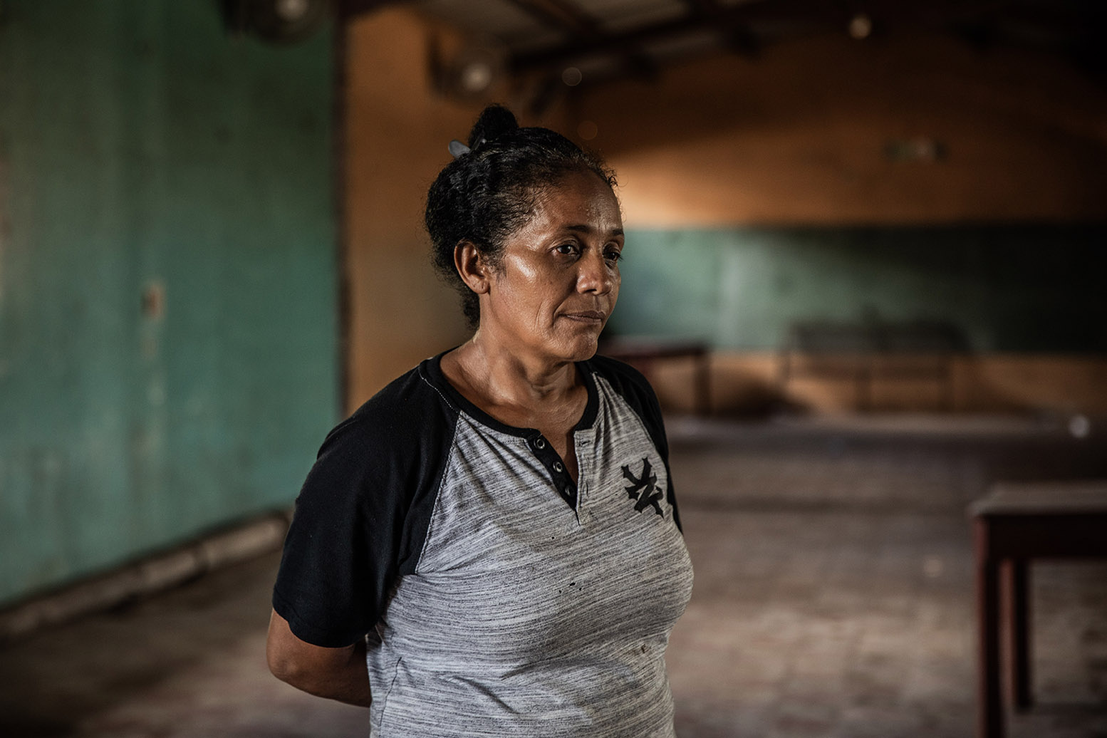 Una mujer retrada en un salón de clases vacío.