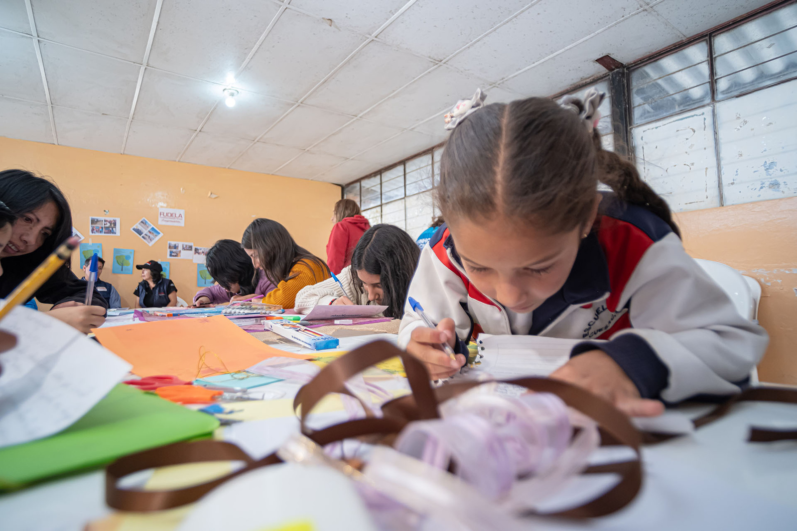 Una niña dibujando en un salón de clases.