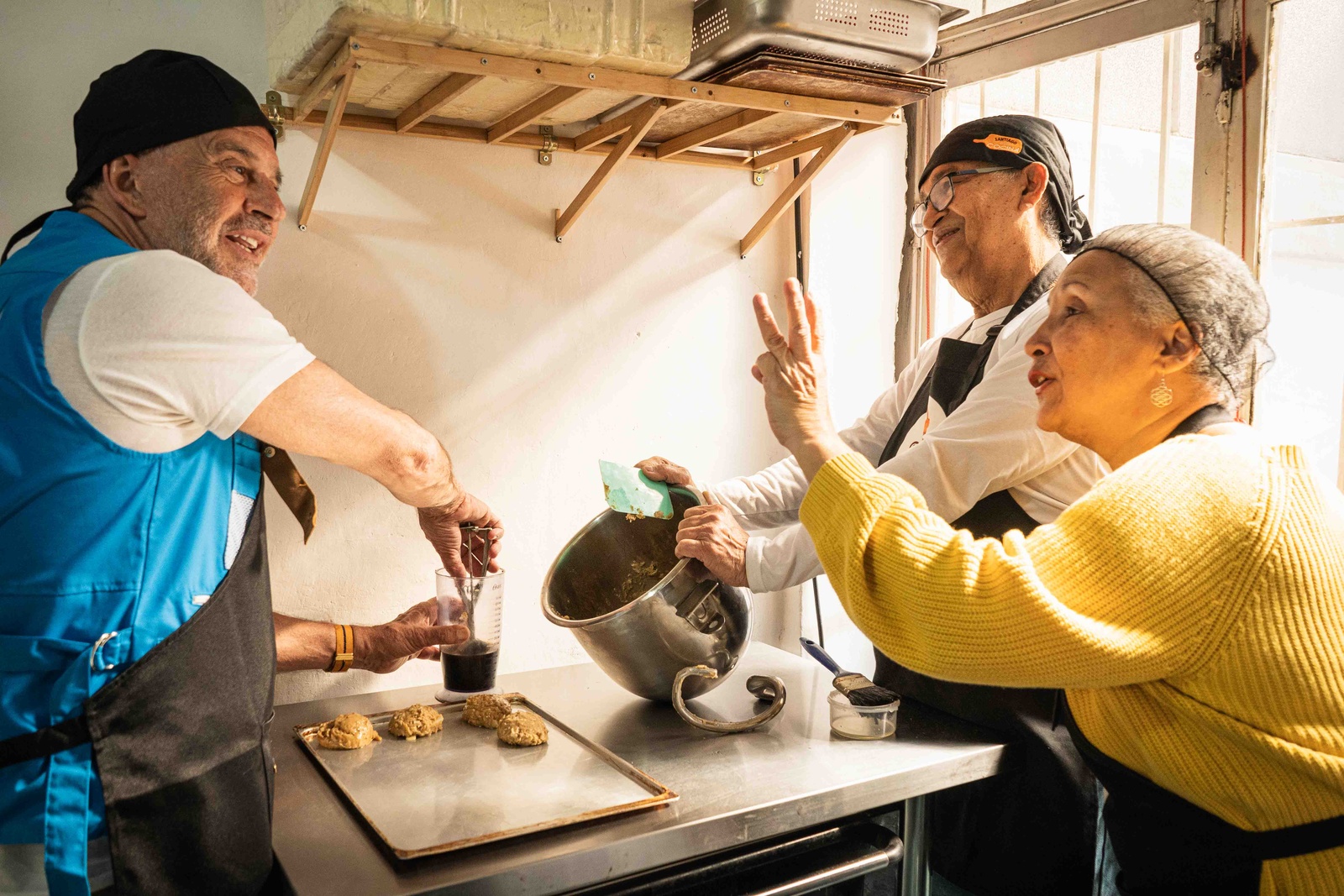 Tres personas preparando alimentos en una cocina.