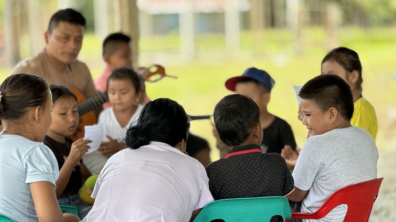 Niños y niñas sentados en mesa redonda.