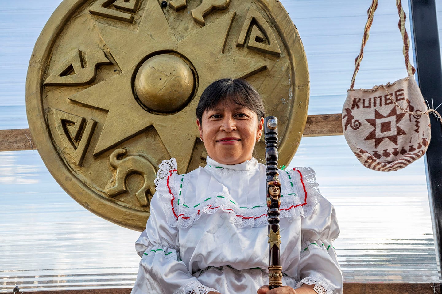 Una mujer posa para la cámara delante de un símbolo que representa el sol.