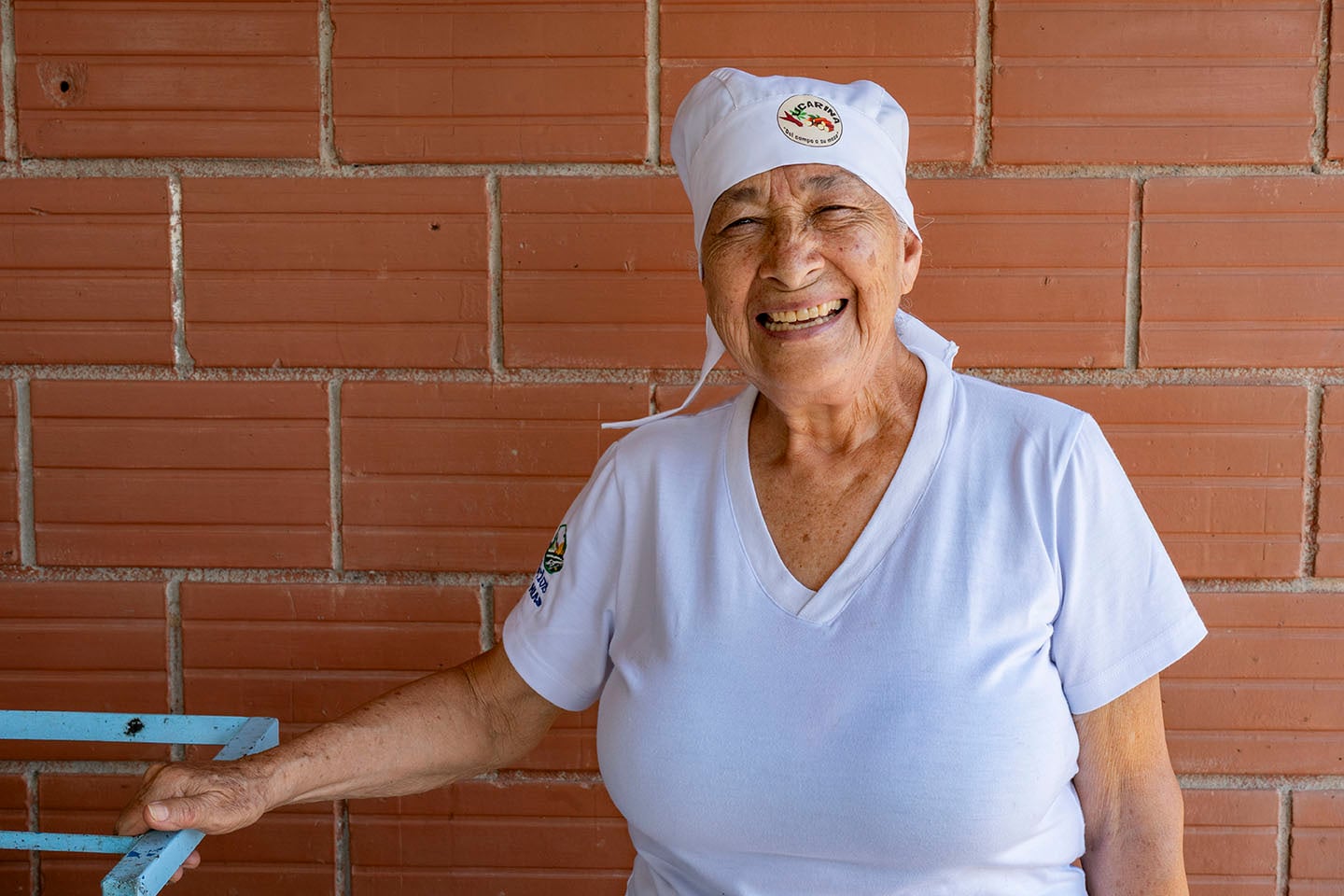 Una mujer con ropa de panadera posa para una foto sonriendo.
