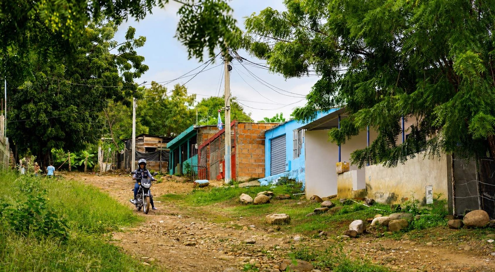 Una moto con su conductor descienden por una calle sin pavimentar del barrio las Delicias 
