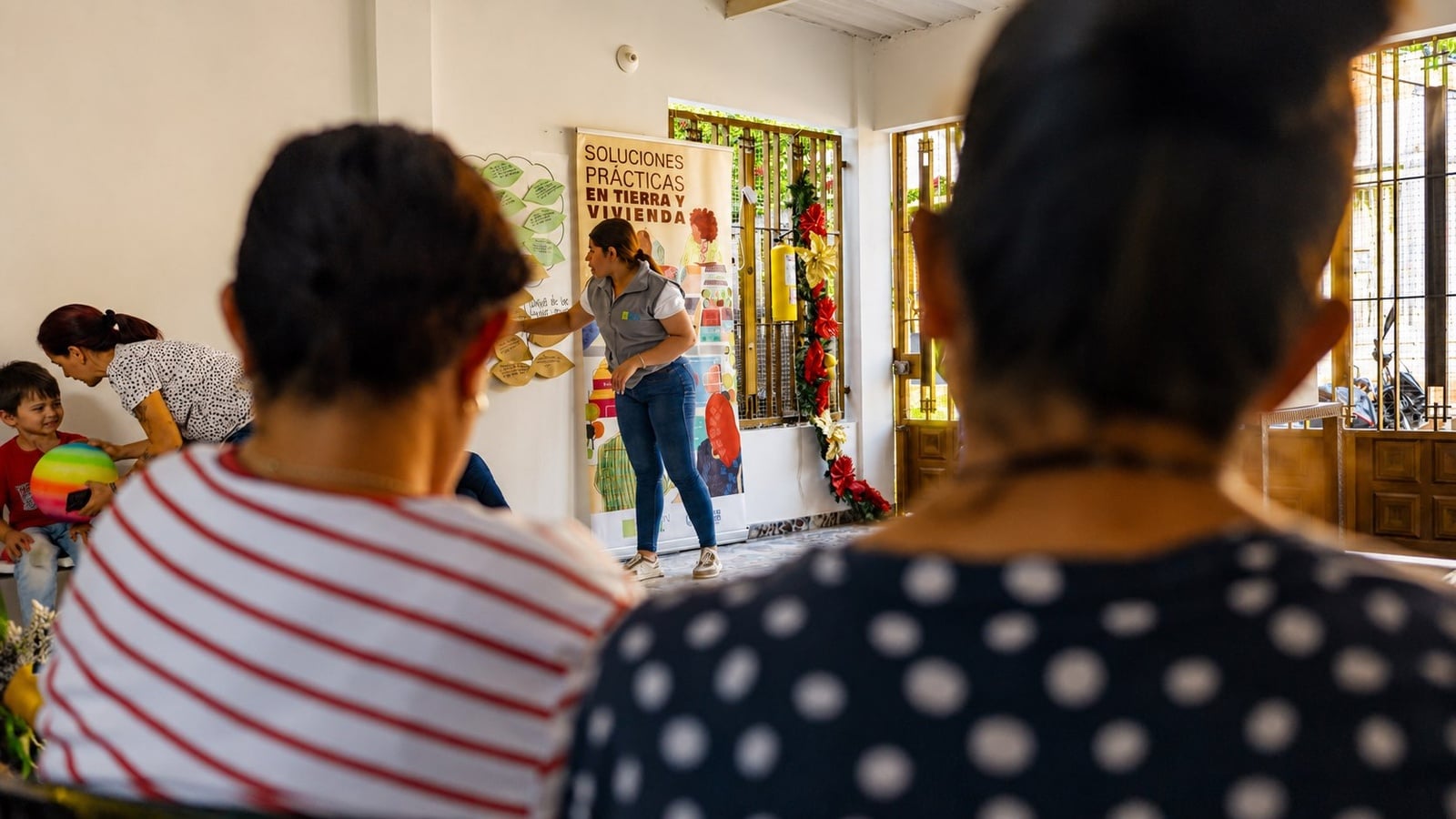 Persona facilitadora de taller y mujeres sentadas escuchando 