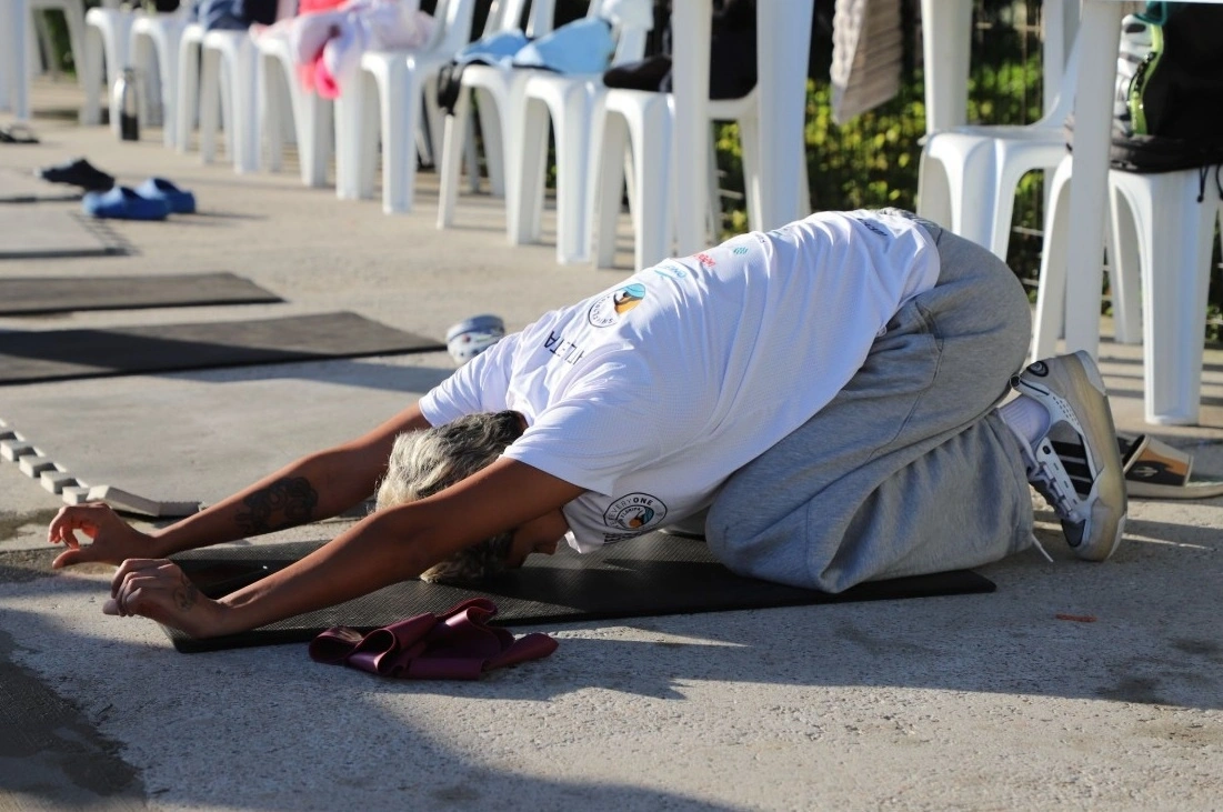 Una mujer con ropa deportiva sentada en el suelo con sus brazos hacia el frente cubriéndose la cabeza