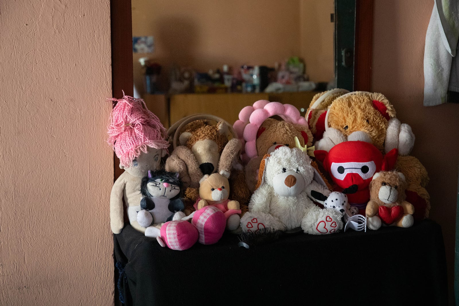 Peluches y muñecas alineados sobre un mueble de manera ordenada.