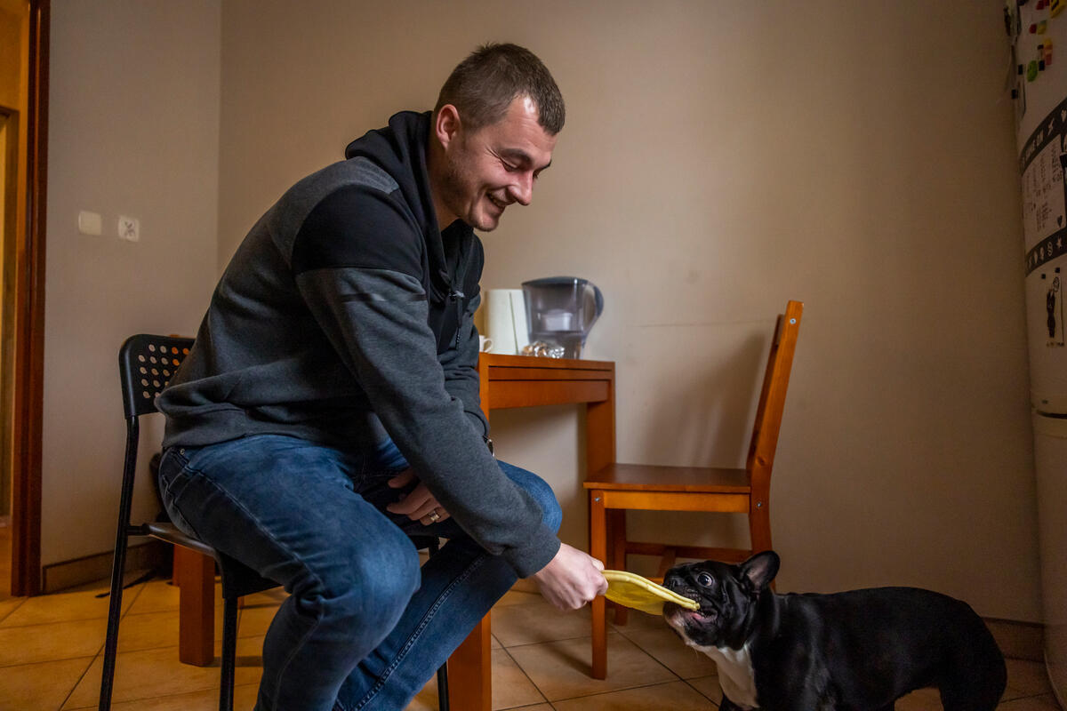 Dmytro juega con Bella, su mascota, en la cocina de su apartamento en Cracovia.