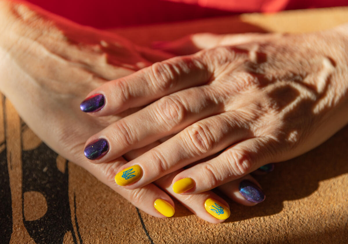 Manos de mujer con uñas pintadas en morado y amarillo