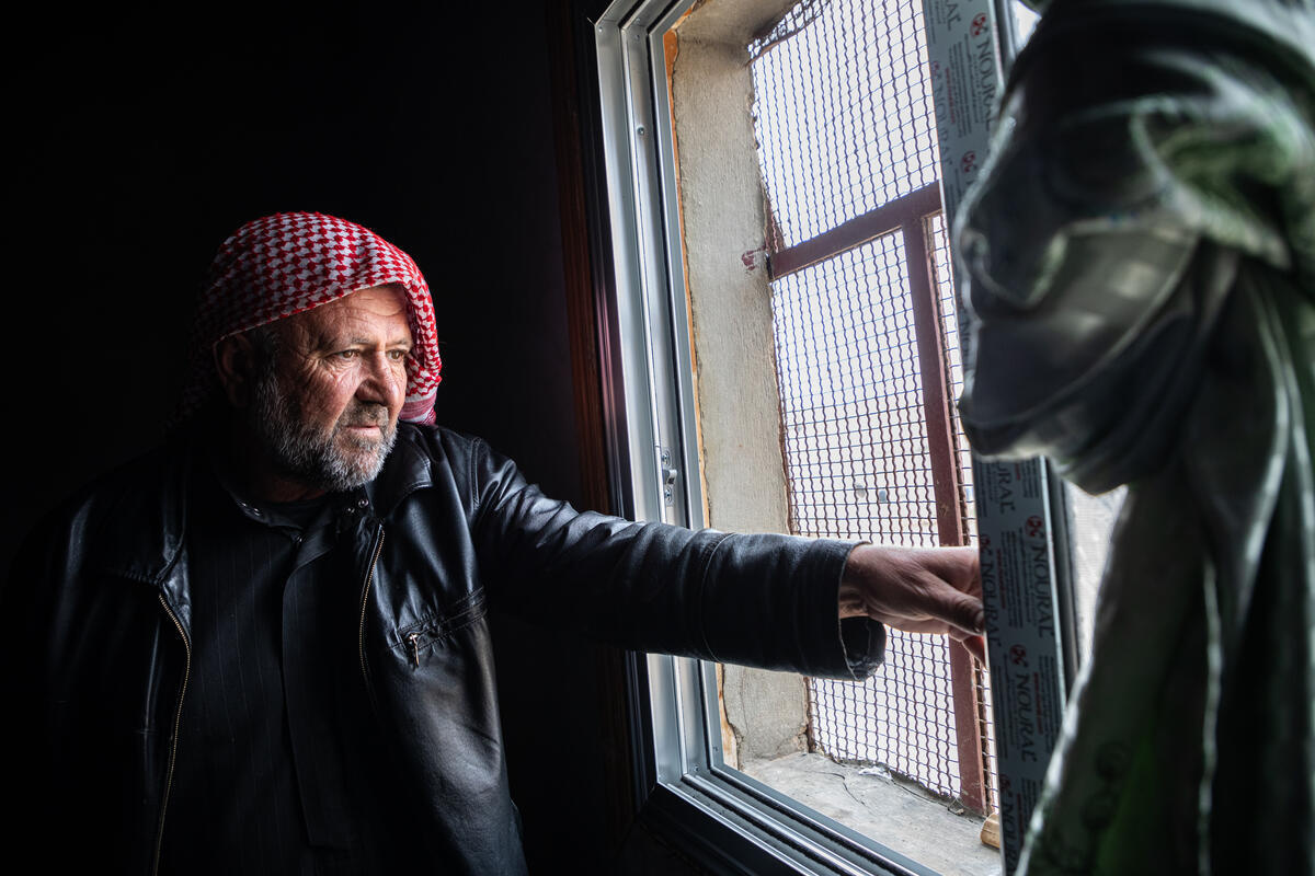 Un hombre con un pañuelo de cuadros rojos y blancos en la cabeza junto a una ventana