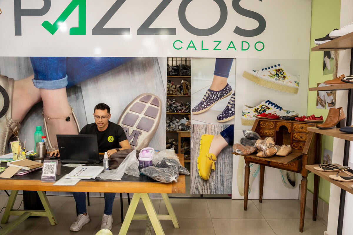 Un hombre sentado detrás de un mostrador en una tienda de zapatos.