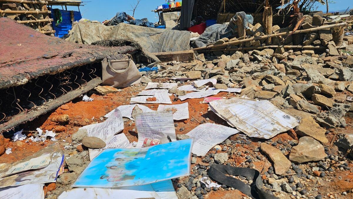 Trabajos escolares empapados por la lluvia esparcidos alrededor de las ruinas de una casa