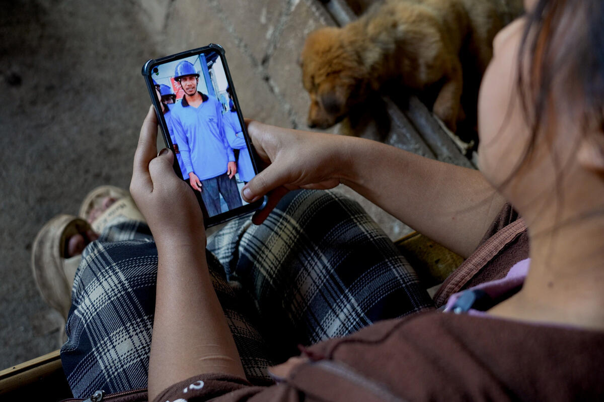 Una mujer observa una foto de un hombre con uniforme azul y casco en su teléfono móvil