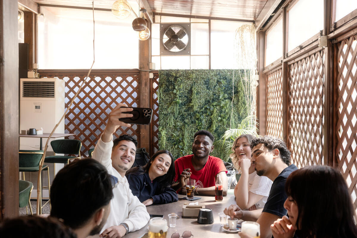 Un grupo de jóvenes tomándose una selfie sentados a la mesa un bar.