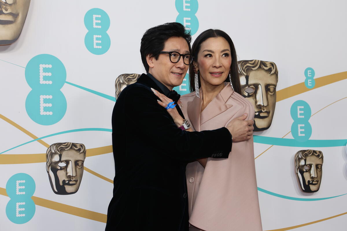 United Kingdom. Actors Ke Huy Quan and Michelle Yeoh wearing a blue ribbon in solidarity with refugees at the EE BAFTA Film Awards 2023