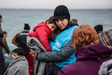 Una trabajadora de ACNUR cubre a un niño refugiado con una manta, luego de que la embarcación en la que él viajaba llegara a Lesvos, una isla griega.