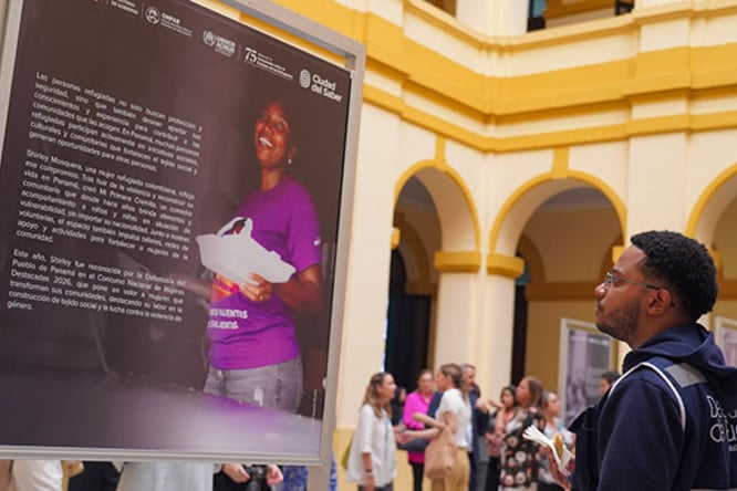 Un joven mirando un panel fotográfico y textual en una exposición.