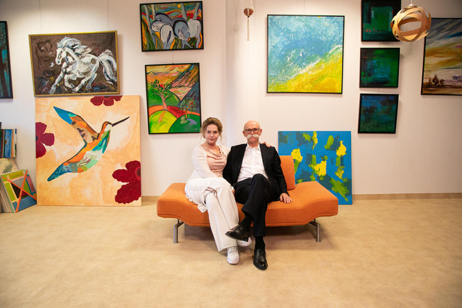 Una pareja (a la derecha, la mujer; a la izquierda, el hombre) sentada en un sofá en una galería de arte