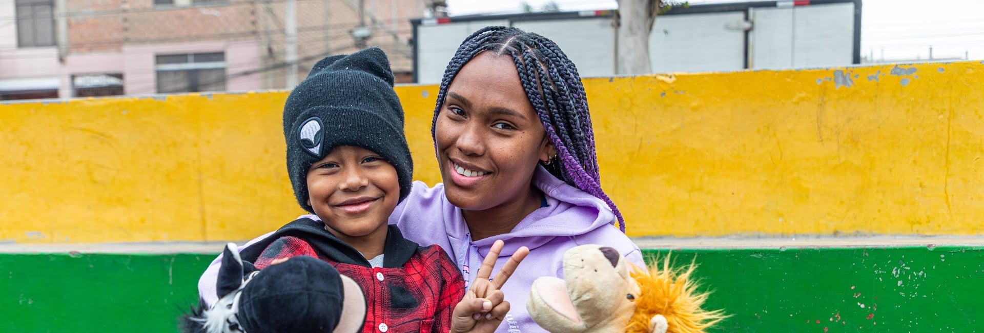 Una mujer y un niño que tiene sentado en sus regazos posan para la cámara sonriendo.