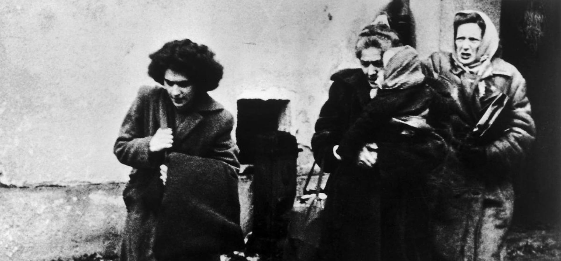 Fotografía en blanco y negro de tres mujeres con un niño que llegan a un campamento de refugiados en Austria