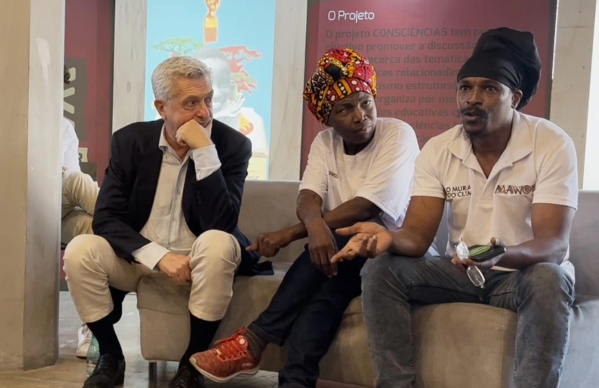 Tres personas sentadas hablando durante un evento público.