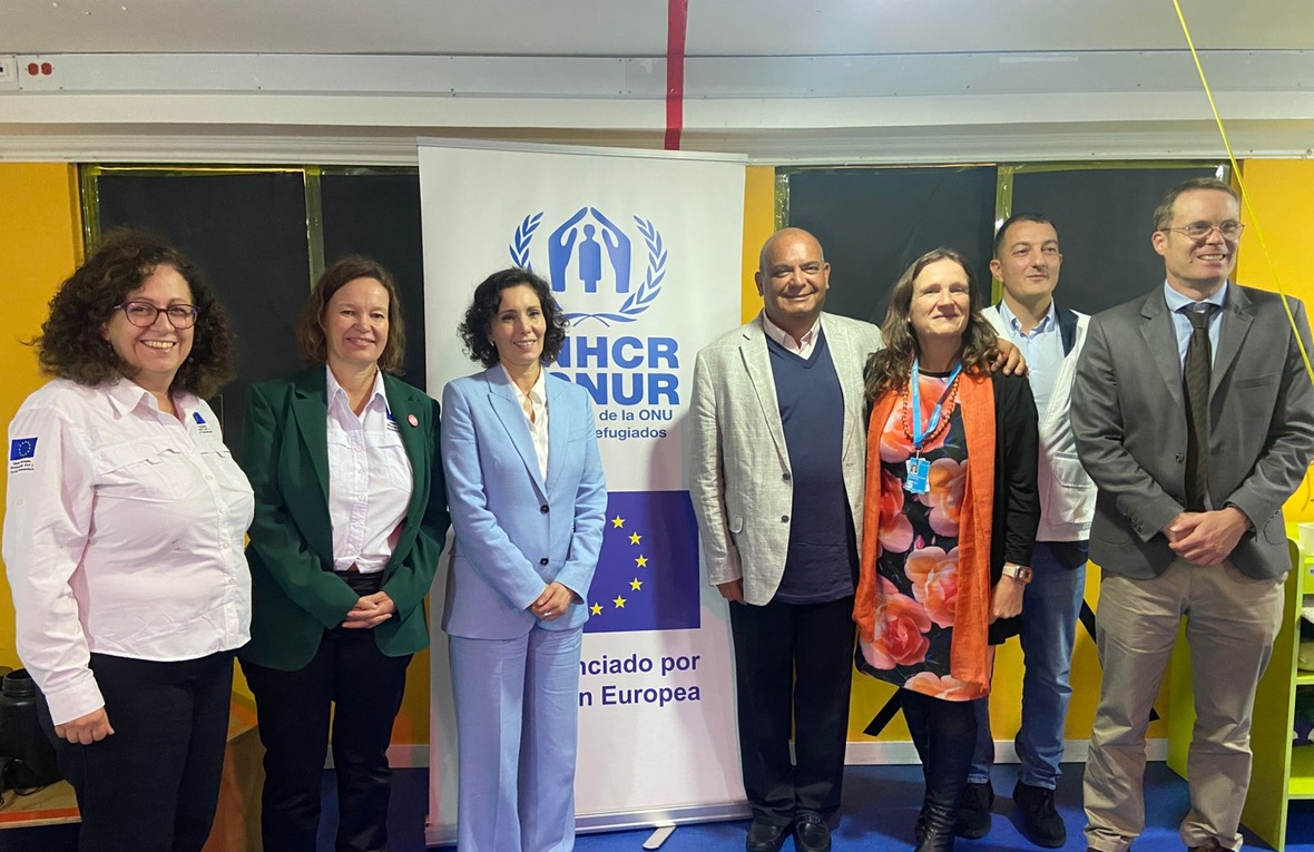 Cuatro mujeres y tres hombres posan para la foto frente a un letrero con el logo de ACNUR y la Unión Europea