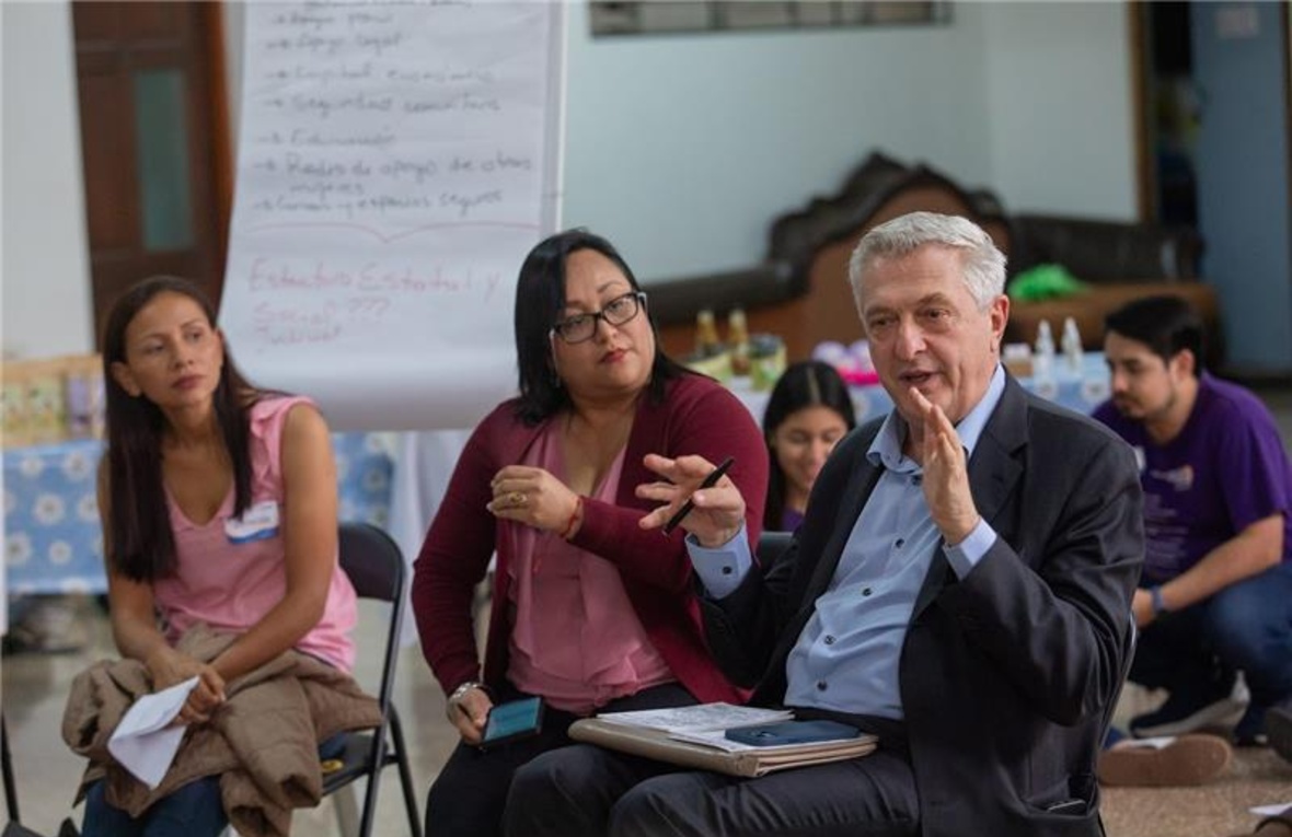 Dos mujeres y un hombre conversan sentados en un salón.