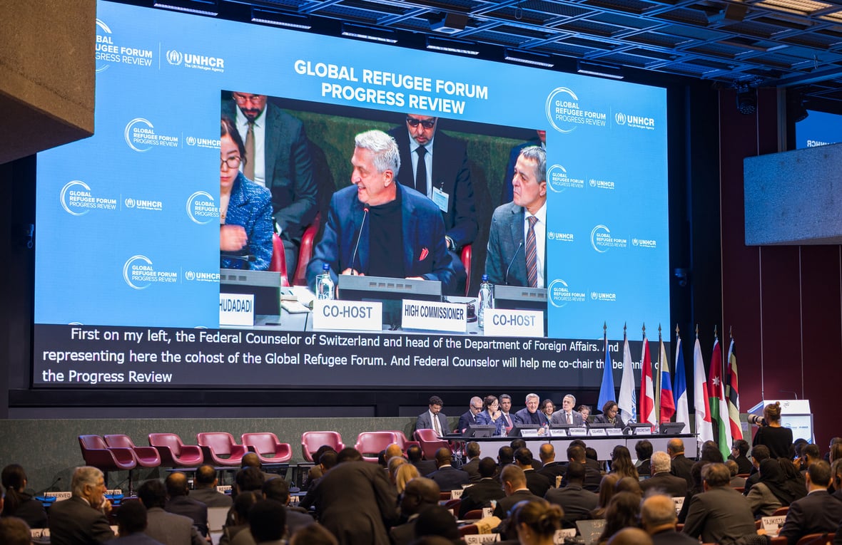 Un hombre habla en una pantalla gigante ante el público que asiste a la sala de conferencias