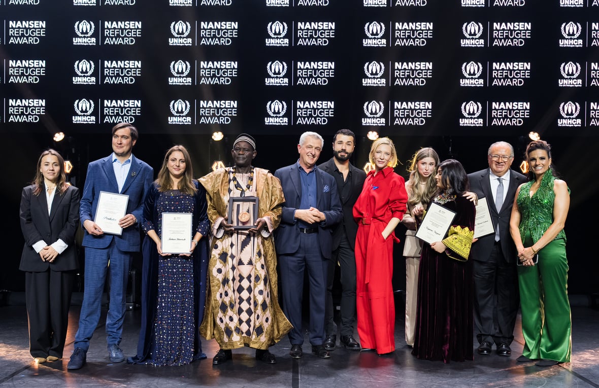 Siete mujeres y cuatro hombres posan sobre un escenario de entrega de premios