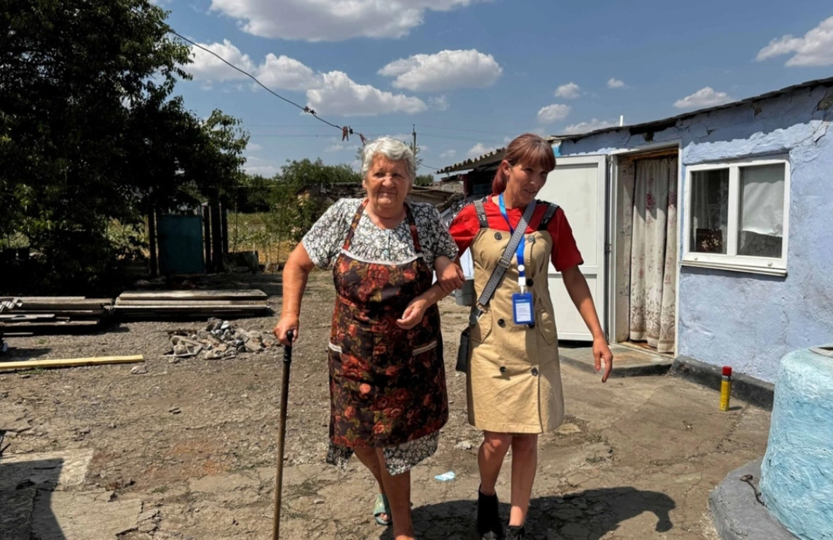 Mujer ucraniana mayor caminando con una facilitadora social